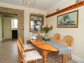 A dining room with wooden table and chairs with cushions flowers in a vase and a horse painting on the wall at 2 Crosslands in Stockton-On-The-Forest