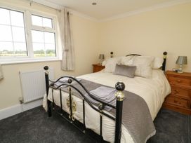 A bedroom with a black and gold metal bed frame two wooden bedside tables with lamps and a window with curtains at 2 Crosslands in Stockton-On-The-Forest
