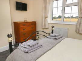 A bedroom with a bed with folded towels on it a wooden chest of drawers a wall-mounted television and a window at 2 Crosslands in Stockton-On-The-Forest