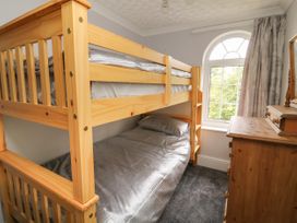 A bedroom with wooden bunk beds a wooden dresser and an arched window with curtains at 2 Crosslands in Stockton-On-The-Forest