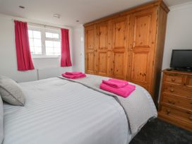 A bedroom with a bed with white and grey bedding pink towels on the bed wooden wardrobes and a small wooden dresser with a television 2 Crosslands Stockton-On-The-Forest