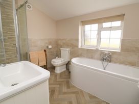 A bathroom with a bathtub under a window a toilet a shower cubicle a sink and a towel rack at 2 Crosslands in Stockton-On-The-Forest