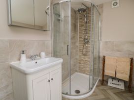 A bathroom with a corner shower enclosure a sink with cabinet a mirrored cabinet above and towels on a wooden rack at 2 Crosslands in Stockton-On-The-Forest