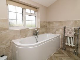 A bathroom with a white bathtub under a window and a towel hanging on a metal radiator at 2 Crosslands in Stockton-On-The-Forest