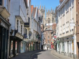 A narrow street with shops and signs and a cathedral in the background at 2 Crosslands in Stockton-On-The-Forest