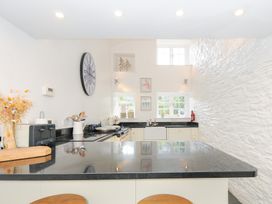 A kitchen with black countertop white cabinets a stove a clock and windows at Quay House in Charlestown