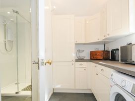 A utility room with white cabinets washing machine and a shower enclosure at Quay House in Charlestown