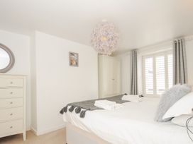A bedroom with a bed towels a chest of drawers a wardrobe and a window with curtains at Quay House in Charlestown