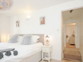 A bedroom with a bed with grey pillows a white bedside table with a lantern and an open door leading to a hallway at Quay House in Charlestown