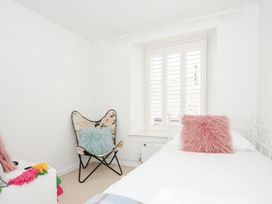 A bedroom with a single bed, window with shutters, butterfly chair with a cushion at Quay House in Charlestown
