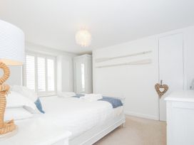 A bedroom with white walls a bed with white bedding and blue throw pillows wooden oars on the wall and a wardrobe at Quay House in Charlestown