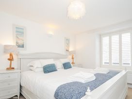 A bedroom with a large white bed blue cushions white folded towels and bedside tables with lamps at Quay House in Charlestown
