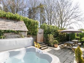 An outdoor patio area with a hot tub wooden picnic tables with umbrellas and greenery at Quay House in Charlestown