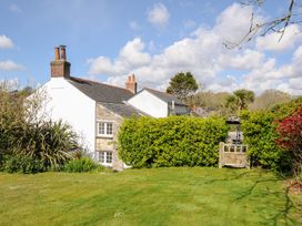 A garden with green lawn and shrubs next to a white and stone house with chimneys at Quay House in Charlestown