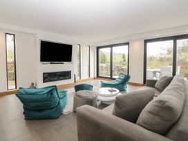A living room with a grey sofa teal bean bags a round white coffee table a wall mounted tv and large windows at 2 White Rock Court Paignton