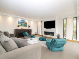 A living room with a gray sofa teal bean bag chairs a wall-mounted TV and a fireplace at 2 White Rock Court in Paignton