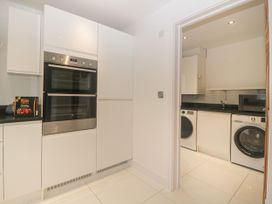 A kitchen with double oven and cabinets next to a utility room with washing machine and dryer at 2 White Rock Court in Paignton
