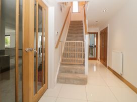 A hallway with tiled floor a carpeted staircase and wooden doors at 2 White Rock Court in Paignton