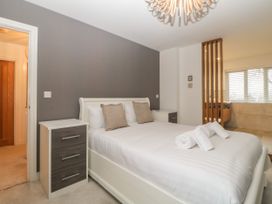 A bedroom with a white bed and bedside tables beside a window with blinds at 2 White Rock Court in Paignton