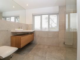 A bathroom with a floating wooden vanity sink a window with blinds a toilet and a wall radiator at 2 White Rock Court in Paignton