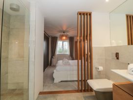 A bedroom with a white bed and towels with a bathroom featuring a shower toilet and sink at 2 White Rock Court in Paignton