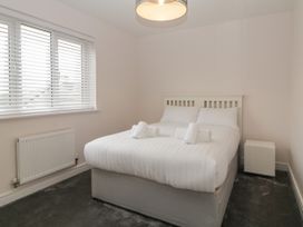 A bedroom with a double bed with white bedding and rolled towels next to a window at 2 White Rock Court in Paignton