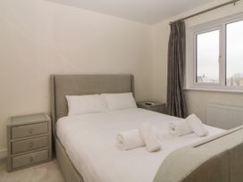 A bedroom with a bed with four rolled white towels on it and two bedside tables at 2 White Rock Court in Paignton