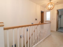 A staircase with white railings and wooden handrails in a hallway with beige carpet at 2 White Rock Court Paignton