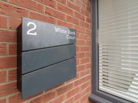 A black sign with the number 2 and White Rock Court on a brick wall next to a window with blinds at 2 White Rock Court in Paignton