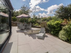 A patio area with outdoor furniture including a table with umbrella and chairs surrounded by plants at 2 White Rock Court in Paignton