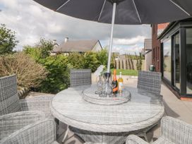 A patio with a round glass-top wicker table and chairs under a large umbrella at 2 White Rock Court in Paignton