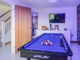 A game room with a blue pool table a wall-mounted television and board games at 2 White Rock Court in Paignton