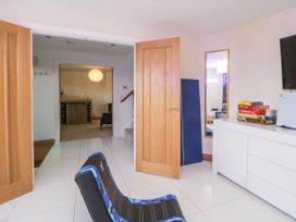 A room with white tiled floor blue chair wooden doors and a white cabinet with board games at 2 White Rock Court in Paignton