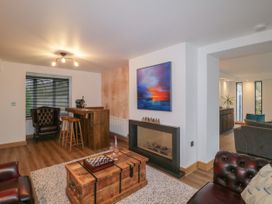 A living room with leather chairs a wooden coffee table a fireplace a wall painting and a wooden bar at 2 White Rock Court in Paignton
