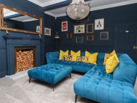 A living room with a blue sofa and wooden fireplace at Kexby House