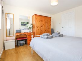A bedroom with a bed with folded towels a wooden wardrobe a wooden dressing table with mirror and flowers at Cuddfan in Tremadog