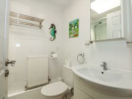 A bathroom with a toilet sink mirror and a painting of a seahorse at Cuddfan in Tremadog