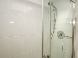 A shower with a glass door and white tiled walls at Cuddfan in Tremadog