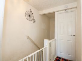 A hallway with a white door a banister a stair gate and a metal bicycle wall decoration at Cuddfan in Tremadog
