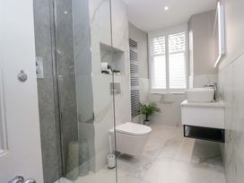 A bathroom with a shower, toilet, sink, and towel rack at Beckmead in Windermere