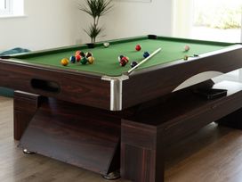 A pool table with billiard balls and a cue stick at Sandy Cove in Praa Sands