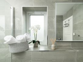 A bathroom with towels and an orchid on a shelf at Sandy Cove in Praa Sands