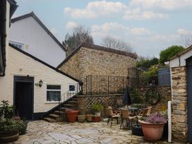 An outdoor area with a stone wall and seating at The Fernery in Colyton