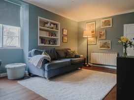 A living room with a sofa and bookshelf at The Fernery in Colyton