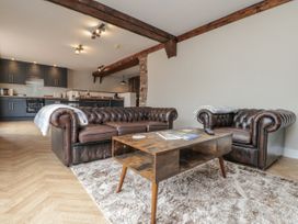 A living room with leather sofas and kitchen area at Betsy's Burrow