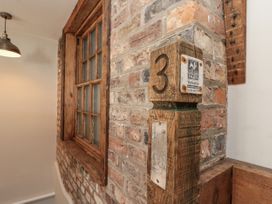 A brick wall with a window and number sign at Betsy's Burrow