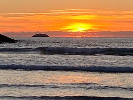 A sunset over the sea with waves and an island in the distance at Kirland in St Kew Highway