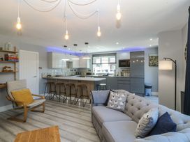 A living room with a kitchen island and bar stools at Ty Glan Morfa in Morfa Bychan