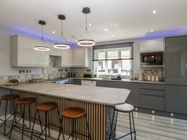 A kitchen with an island and bar stools at Ty Glan Morfa in Morfa Bychan