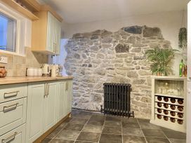 A kitchen with stone wall and cabinets at Waterfall Cottage in Dyserth